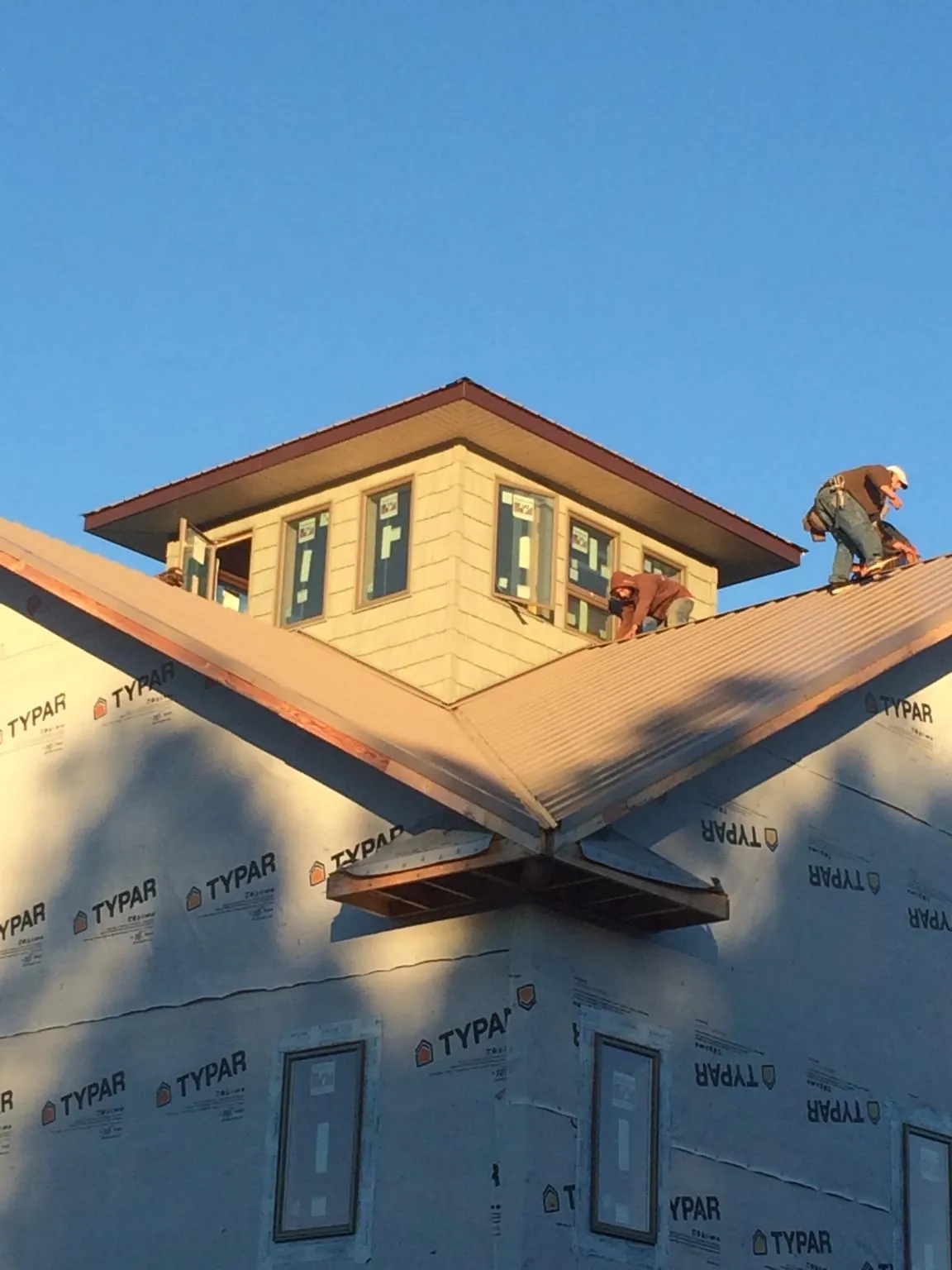 Roofers working around a rooftop cupola on a new metal roof at sunset — Roof Waterproofing in Taylorsville by Roofing Brothers